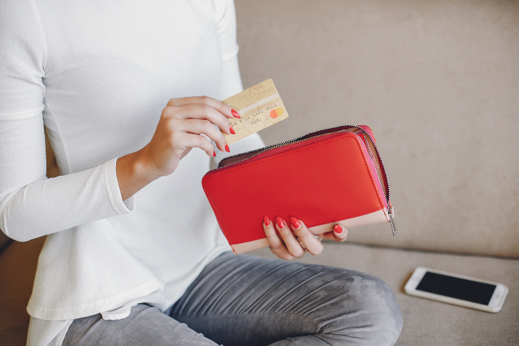 Žena u rukama drži novčanik crvene boje